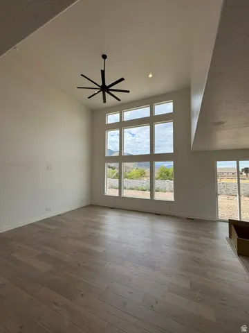 Vaulted ceilings, a contemporary ceiling fan, recessed lighting, expansive windows, and wood-finish flooring