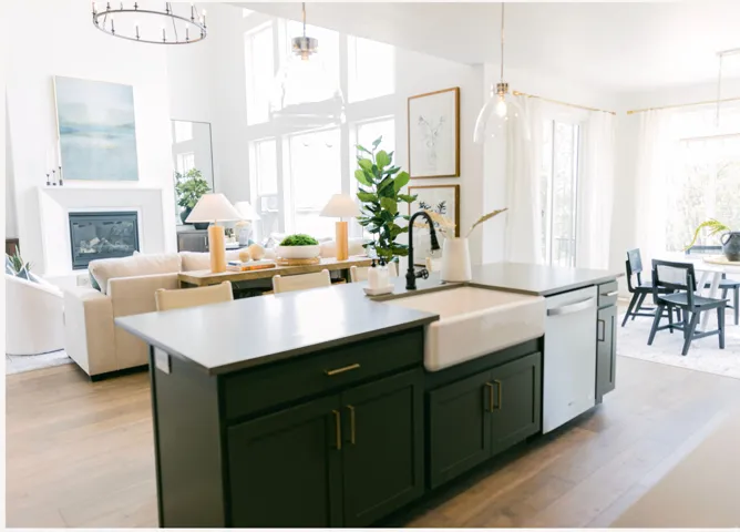 Kitchen island with a white farmhouse sink, matte black faucet, and dark cabinetry