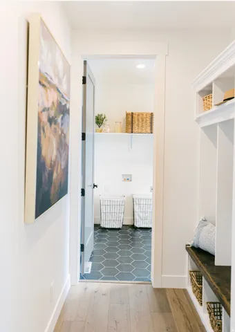 Laundry area featuring hexagon tile flooring, a white wall shelf, and space for appliances