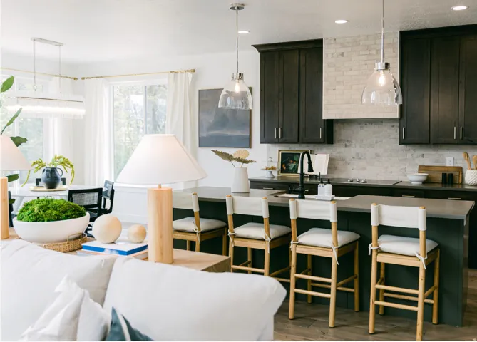 Open-concept kitchen featuring dark wood cabinetry, a light brick-style backsplash, and an island with seating for three