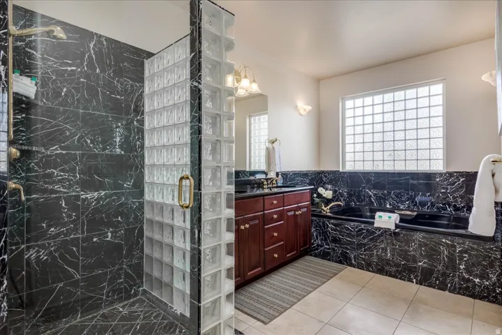 Shower enclosure featuring black marbled tile and a glass block wall