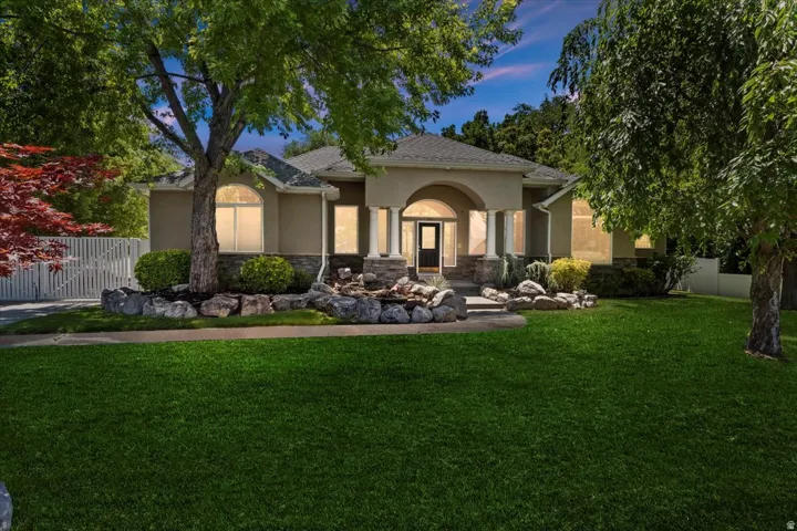 Stucco exterior residence with a stone-clad portico, arched entryway, and decorative columns