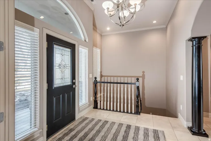 Entryway featuring a black paneled door with decorative glass inserts, sidelight windows with blinds, and an arched transom window