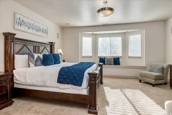 Carpeted bedroom featuring a bay window with an integrated window seat, recessed lighting, and a prominent ceiling light fixture