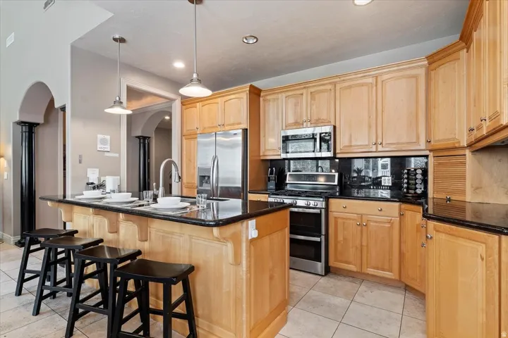 Kitchen featuring light wood cabinetry, dark countertops, and stainless steel appliances