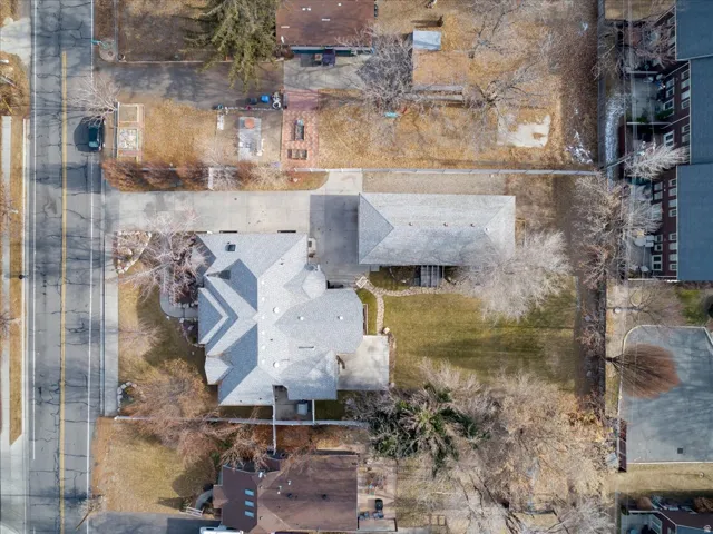 Expansive property featuring a multi-gabled roofline, a substantial driveway, an attached garage, a manicured lawn, and mature trees
