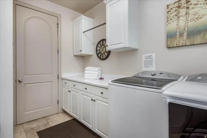 Laundry area featuring white cabinetry, a light-toned countertop, and tile flooring