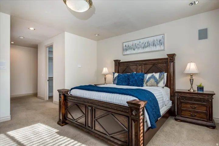 Spacious bedroom featuring neutral wall tones, recessed lighting, and soft carpeting