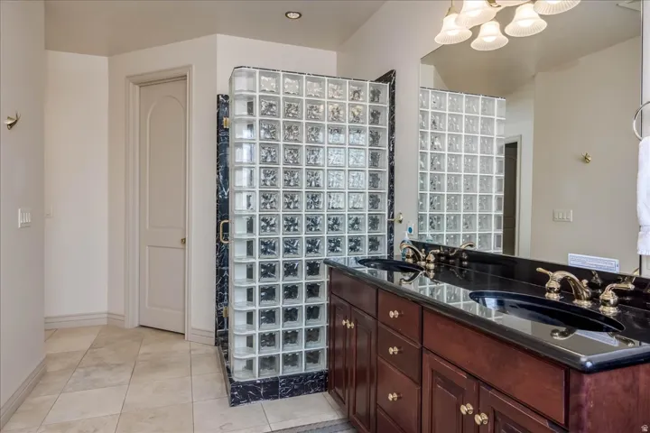 Bathroom featuring a dual vanity with dark wood cabinetry and black countertops, dual undermount sinks, and gold-tone fixtures