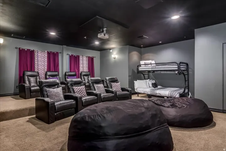 Dedicated media room featuring tiered seating, recessed lighting, a ceiling-mounted projector, and a built-in bunk bed