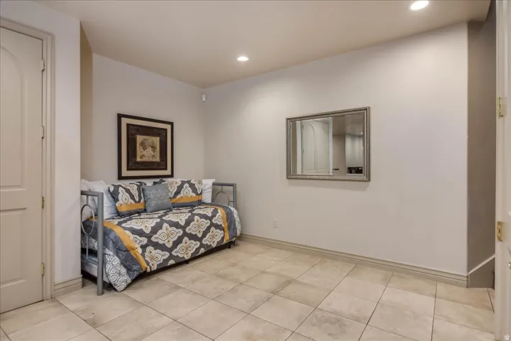 Spacious room featuring tile flooring, neutral wall tones, recessed lighting, and a paneled door
