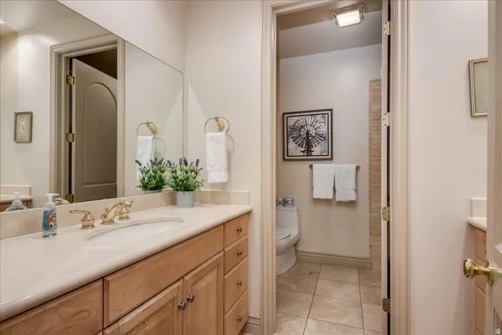 Bathroom vanity with a light-toned countertop, undermount sink, and brass-finish faucet