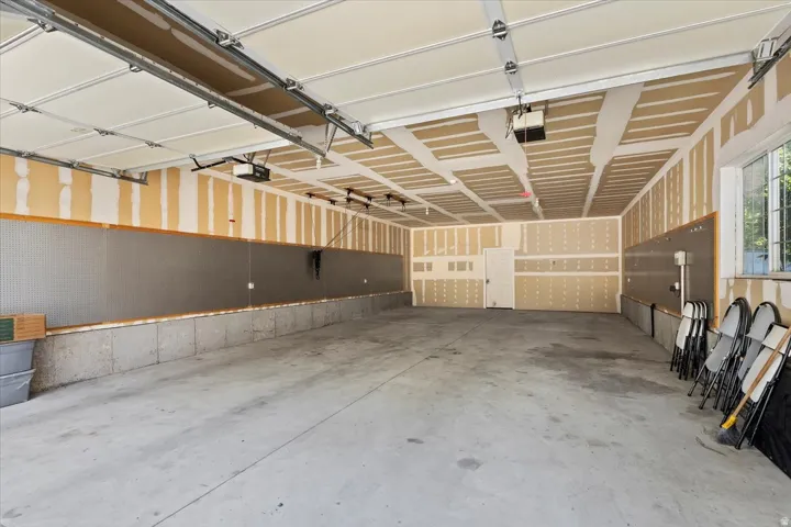 Expansive garage featuring a concrete floor, exposed ceiling joists, and a window for natural light