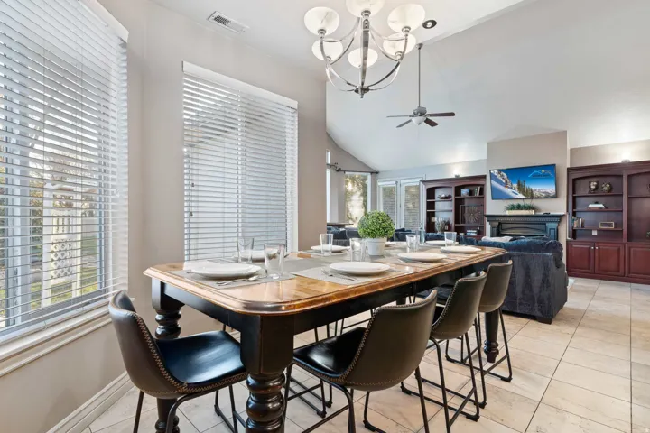 Dining area with a wood-finish table and seating for six, illuminated by a multi-bulb chandelier