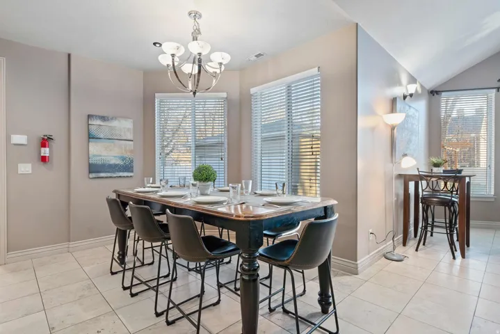 Dining area featuring a central chandelier, tile flooring, and multiple windows with blinds