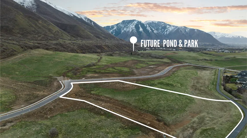 Expansive land parcel featuring established roadways, surrounding green space, and a mountainous backdrop