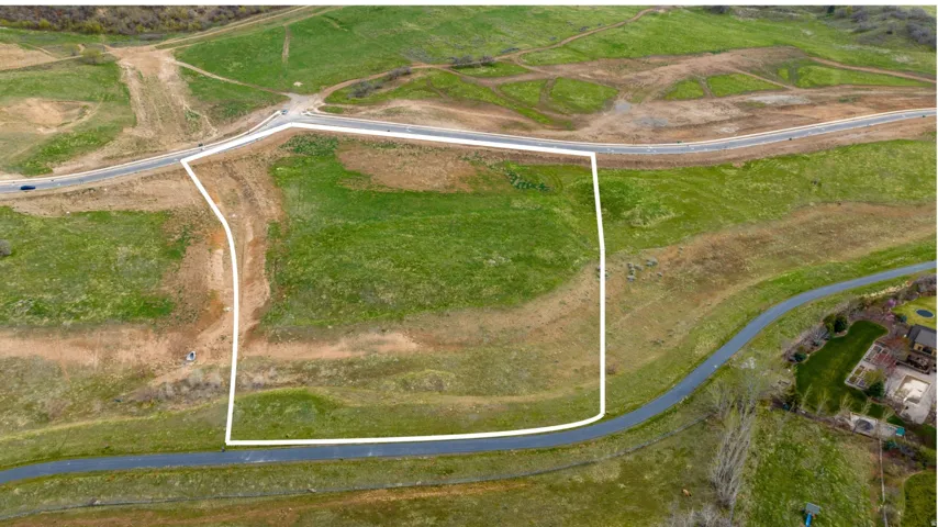 Expansive parcel featuring a defined boundary, surrounding green spaces, and direct road frontage