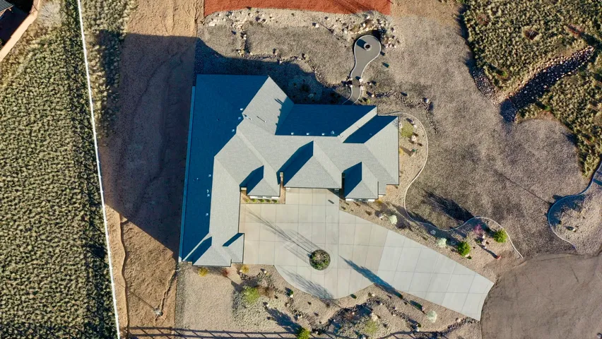 Expansive property featuring a multi-gabled roofline, concrete driveway with a circular accent, and natural desert landscaping