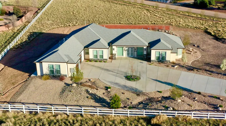 Contemporary ranch-style residence featuring a multi-gable roofline, a curved concrete driveway, and a fenced perimeter