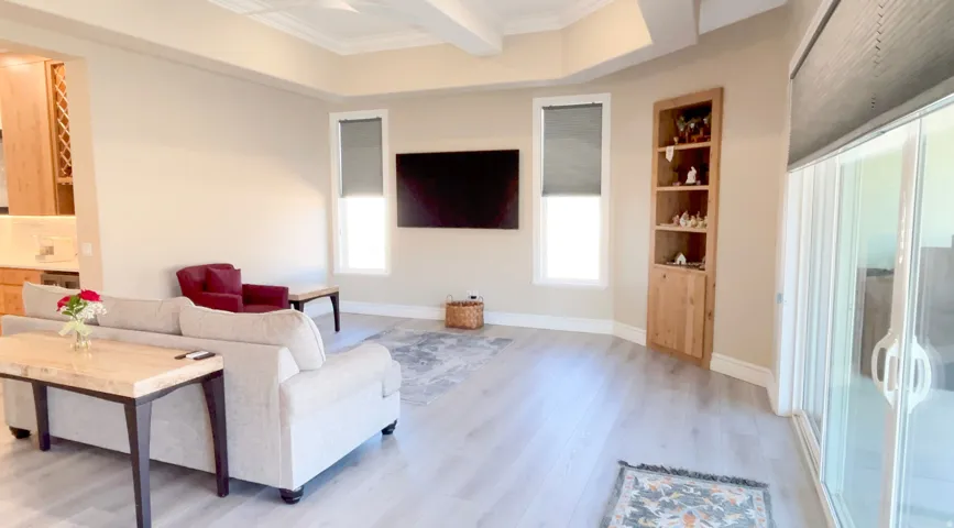 Spacious living area featuring light wood-finish flooring and a coffered ceiling