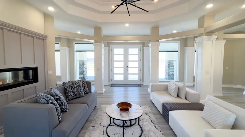 Spacious living area featuring a linear fireplace with paneling surround, light wood-finish flooring, and a coffered ceiling