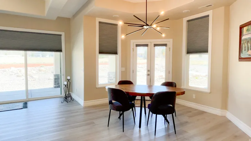 Spacious dining area featuring wood-finish flooring, a modern linear chandelier, and ample natural light from multiple windows