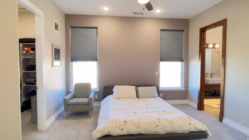 Recessed lighting illuminates this room featuring two windows with privacy blinds, plush carpeting, and a ceiling fan