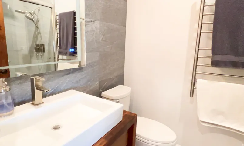 Modern bathroom featuring a rectangular vessel sink with a brushed nickel faucet, a wall-mounted mirrored medicine cabinet, and a toilet