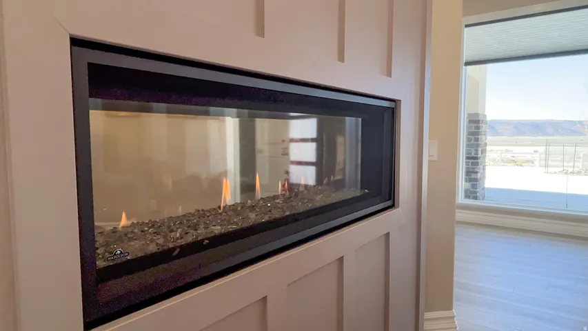 Built-in linear gas fireplace with decorative stones, framed by a panel accent wall