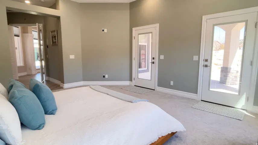 Carpeted room featuring two full-light panel doors with exterior access, crown molding, and a high vaulted ceiling