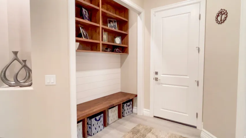 Entryway with built-in wooden shelving, a shiplap accent wall, and a wooden bench