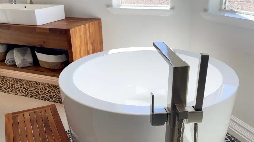 Freestanding soaking tub with a brushed metal floor-mounted faucet