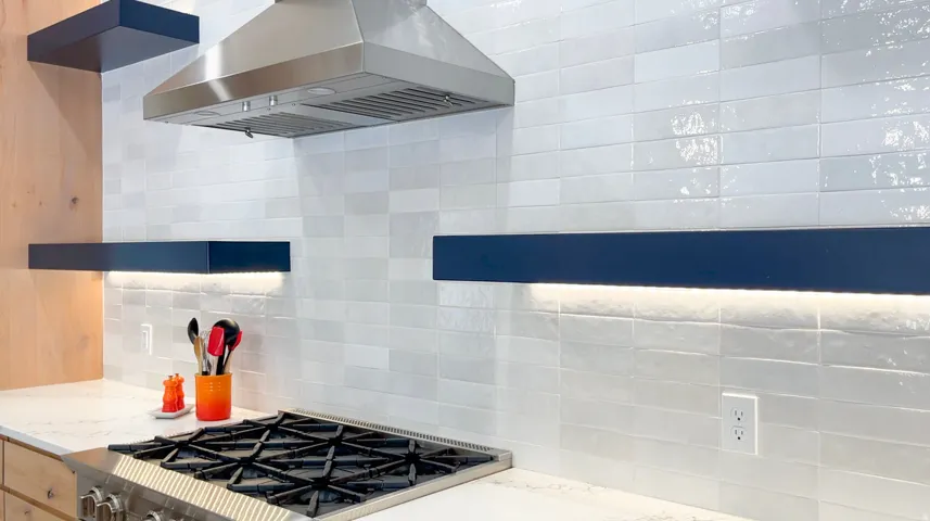 Kitchen features a stainless steel range with a professional-grade hood, white subway tile backsplash, under-shelf lighting, and floating shelves