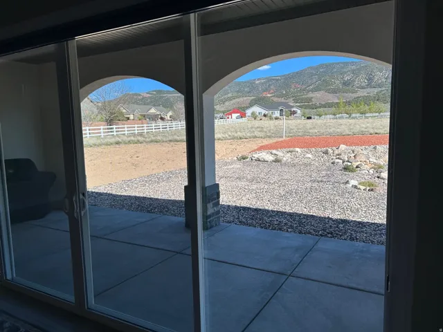 Sliding glass doors opening to a covered patio with arched entries and stone-clad columns