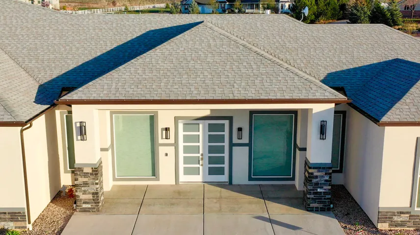 Contemporary exterior featuring a light stucco finish, stone-clad columns, and a modern entry door with frosted glass panels