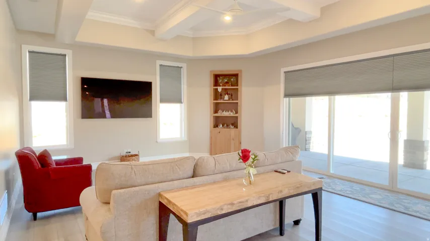 Living area featuring a tray ceiling with exposed beams, recessed lighting, and wood-finish flooring