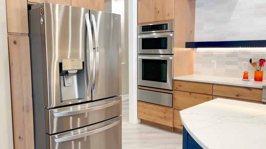 Stainless steel French door refrigerator alongside built-in double ovens and a warming drawer