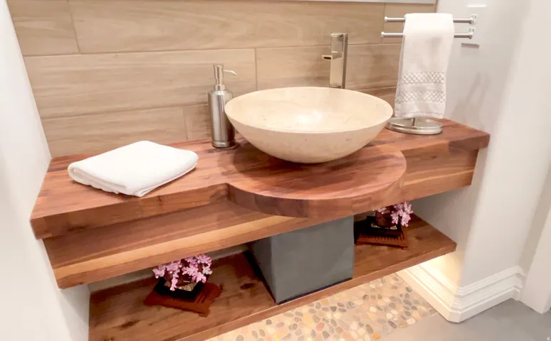 Custom wood-finish vanity featuring a natural stone vessel sink and a wall-mounted faucet