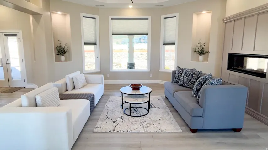 Spacious living area featuring light wood-finish flooring and a contemporary linear fireplace with paneling surround