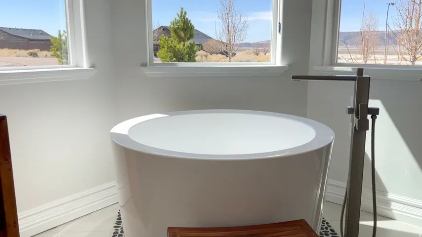 Freestanding soaking tub with a floor-mounted brushed nickel faucet