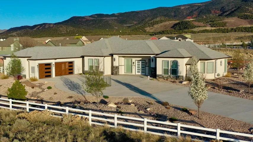 Contemporary stucco exterior with stone accents, a multi-car driveway, and a two-car garage with wood-finish doors