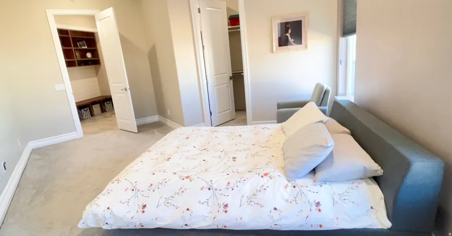 Carpeted bedroom featuring neutral wall tones, white trim, and a window with blinds