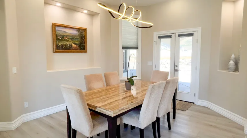 Dining area with light wood-finish flooring, recessed wall niches, and a modern ceiling fixture