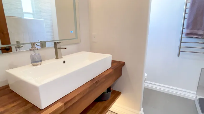 Bathroom featuring a rectangular vessel sink with a brushed nickel faucet, set upon a wood-finish floating vanity