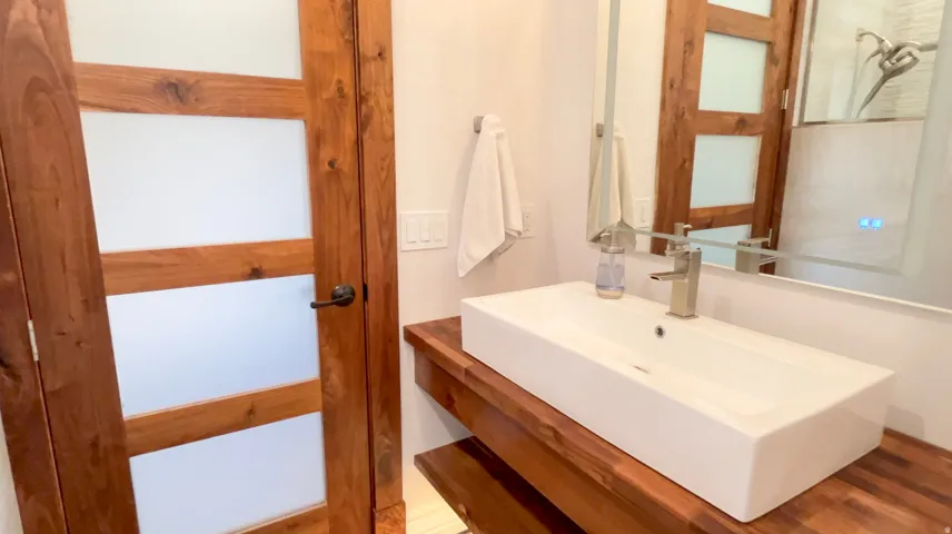 Modern bathroom vanity featuring a rectangular vessel sink, brushed nickel faucet, and natural wood countertop