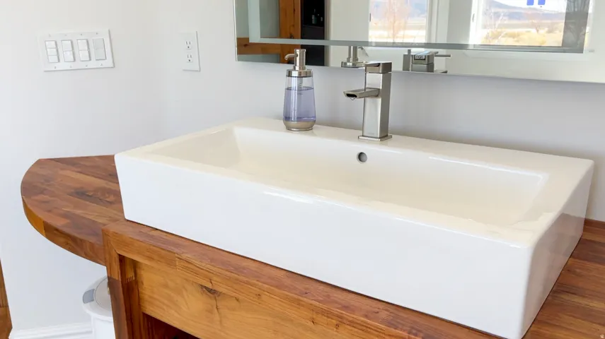 Rectangular vessel sink with a single-handle faucet, set on a wood-finish vanity with an integrated countertop