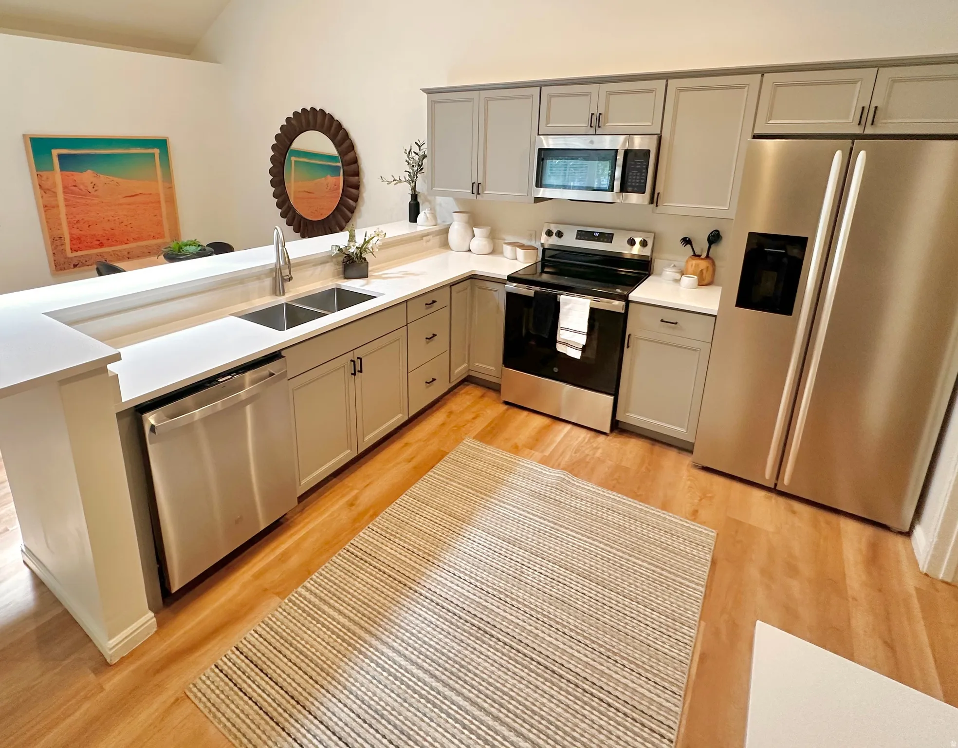 Open-concept kitchen featuring light wood-finish flooring, white countertops, and gray cabinetry