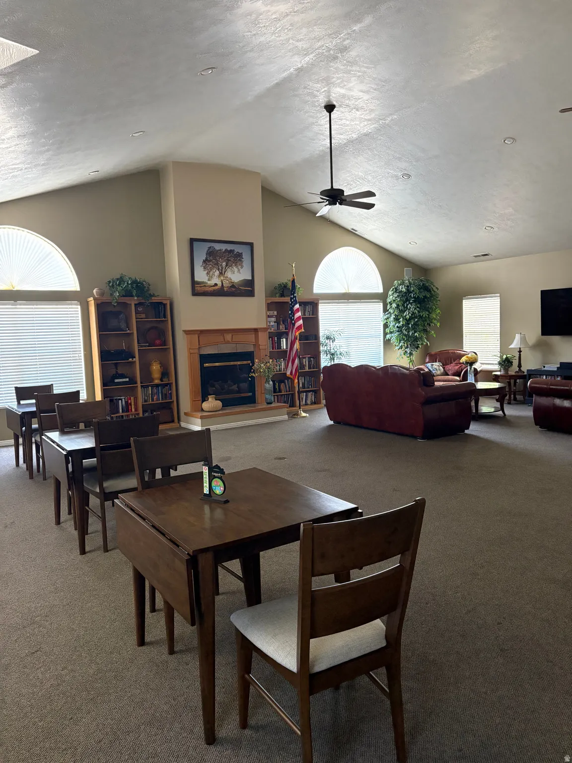 Clubhouse, Spacious gathering area featuring vaulted ceilings, a central fireplace, multiple arched windows, and recessed lighting