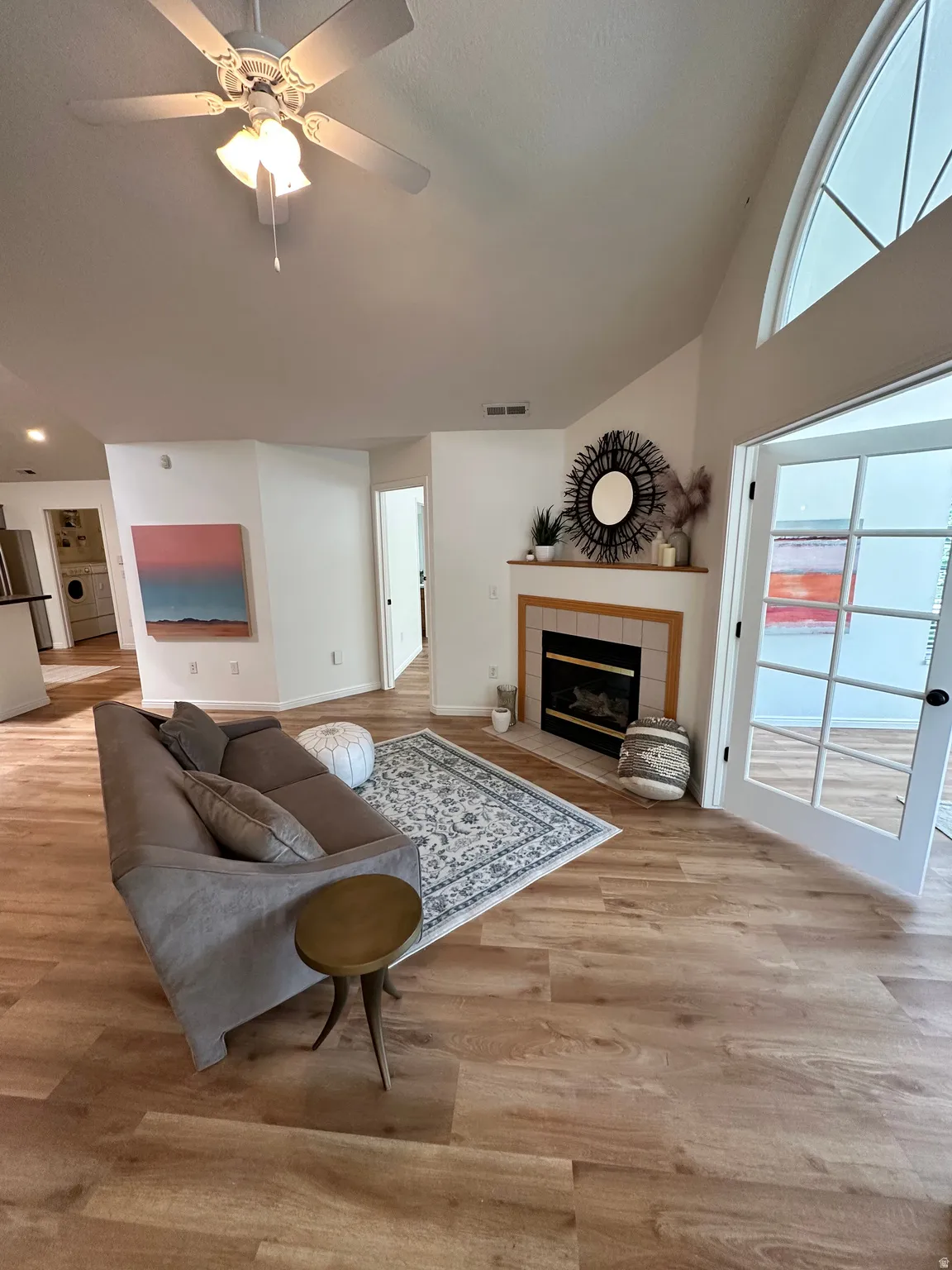 Spacious living area featuring high vaulted ceilings, wood-finish flooring, and a ceiling fan