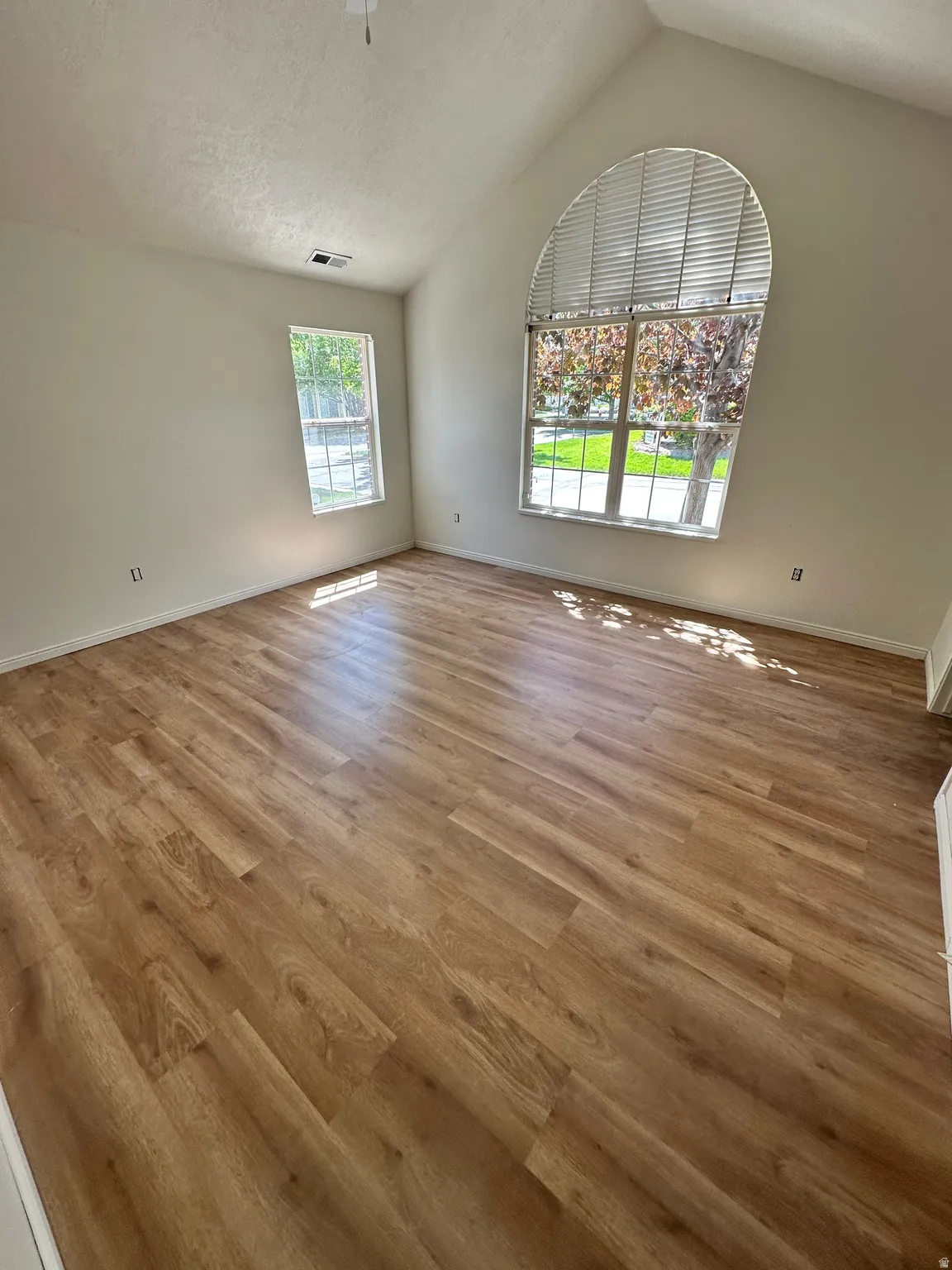 Vaulted ceiling room featuring wood-finish flooring
